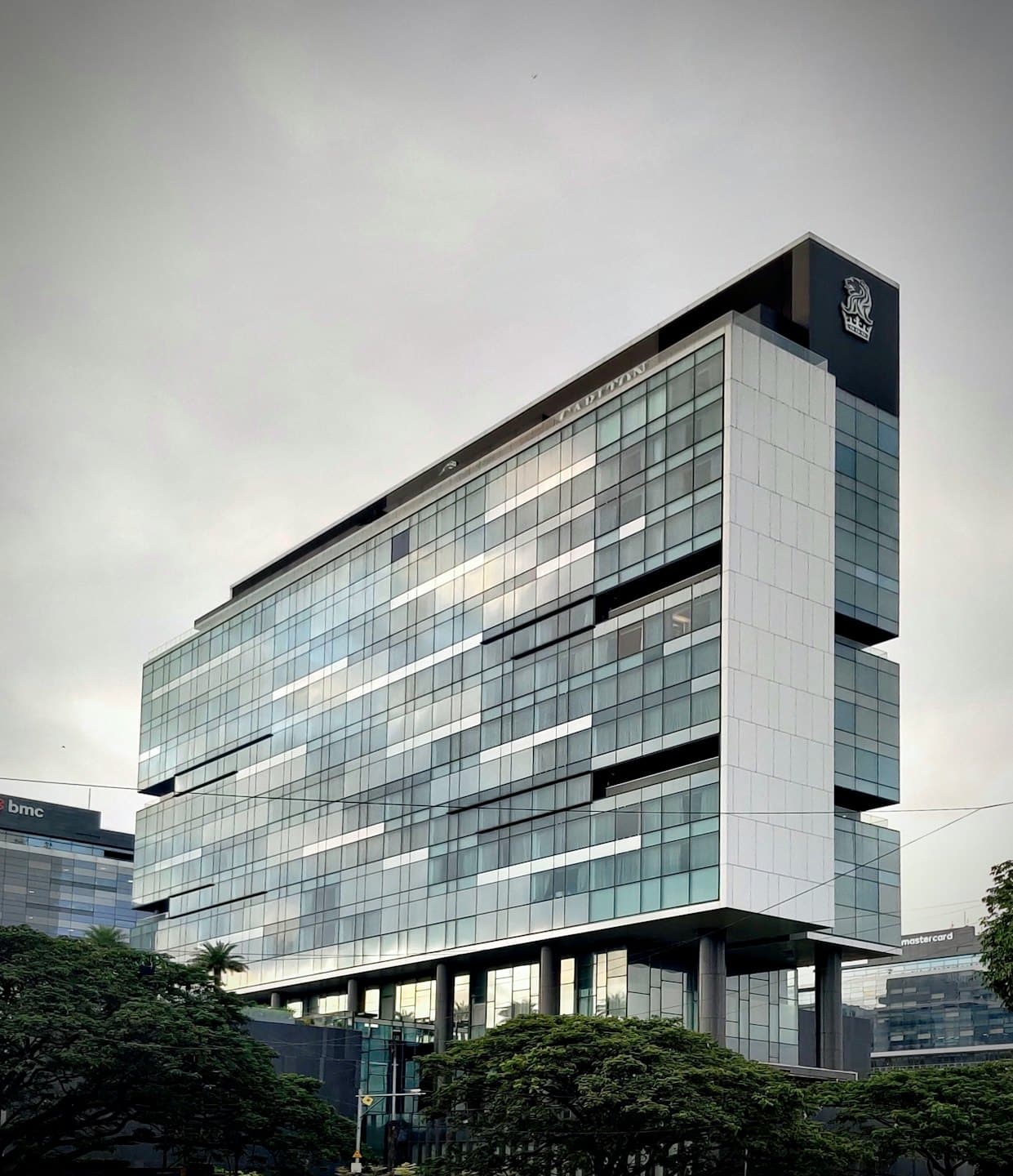 Moderno edificio aziendale con facciata in vetro sotto un cielo coperto.
