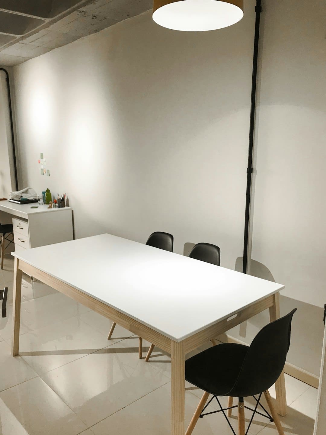 Sala riunioni moderna con tavolo bianco e sedie nere.