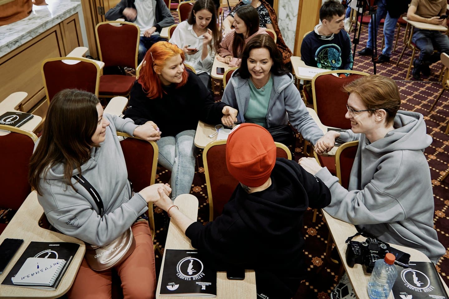 Un team che si tiene per mano in cerchio durante una riunione.