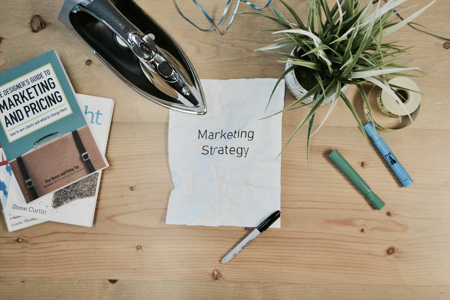 Scrivania in legno con libri di marketing e foglio accartocciato 'Strategia di Marketing'.